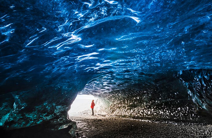 A man standing in an ice cave under a glacier in Iceland